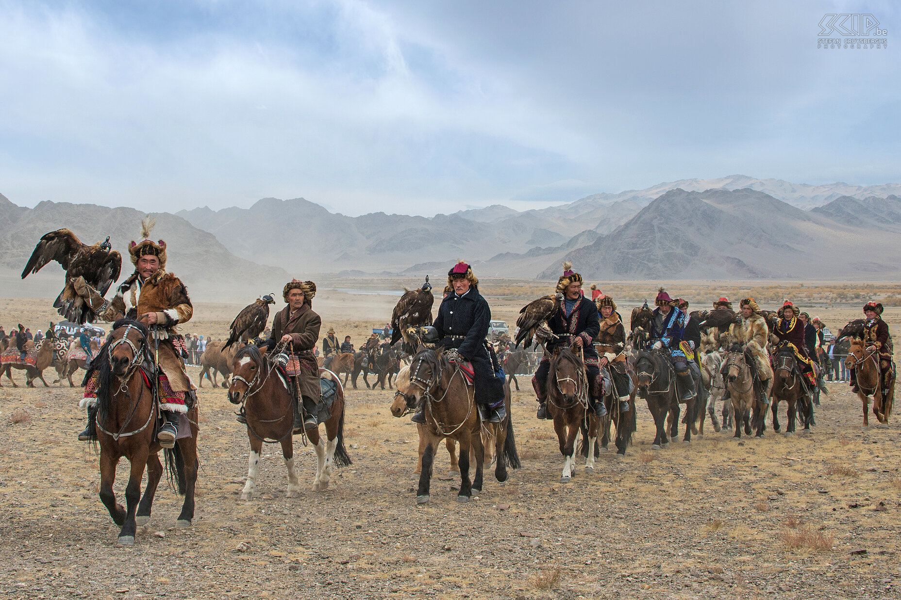 Ulgii - Golden Eagle Festival - Openingsceremonie De adelaarjagers komen vanuit alle windstreken en uit verafgelegen gebieden in het Altai gebergte en sommigen reizen dagen te paard om te komen deelnemen. Het festival begint met een indrukwekkende parade: zeventig arendjagers met op hun arm hun arenden draven voorbij op hun paarden en kamelen, de jongste negen, de oudste tachtig. Ze dragen prachtige traditionele kledij. Nadien worden er verschillende wedstrijden gehouden. Stefan Cruysberghs